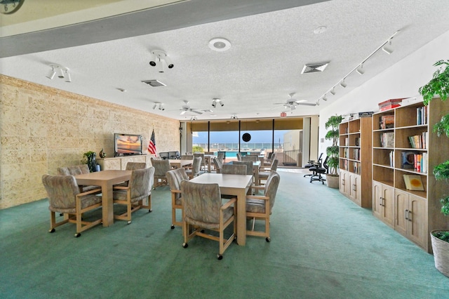 dining space featuring a textured ceiling, carpet floors, track lighting, and ceiling fan