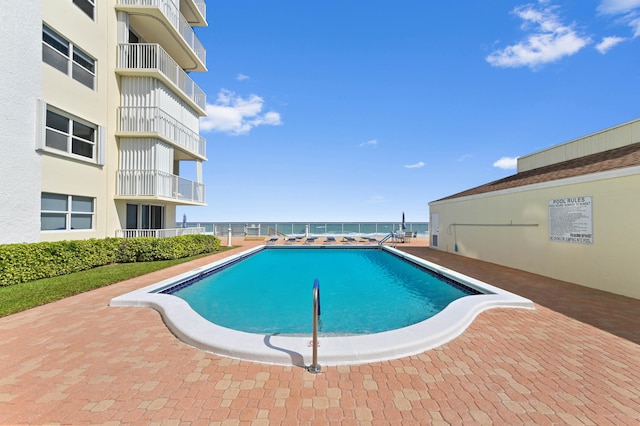 view of swimming pool featuring a patio and a water view