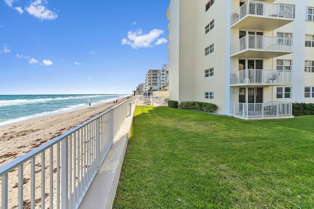 exterior space with a water view, a lawn, and a beach view