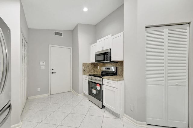 kitchen with backsplash, white cabinets, light stone countertops, light tile patterned flooring, and stainless steel appliances