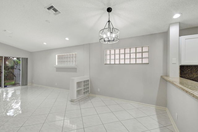 unfurnished dining area with a chandelier, light tile patterned floors, a textured ceiling, and lofted ceiling