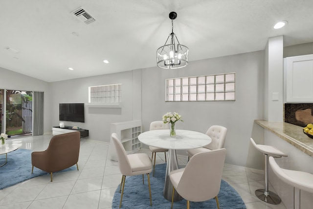 dining space featuring light tile patterned flooring, lofted ceiling, and a notable chandelier