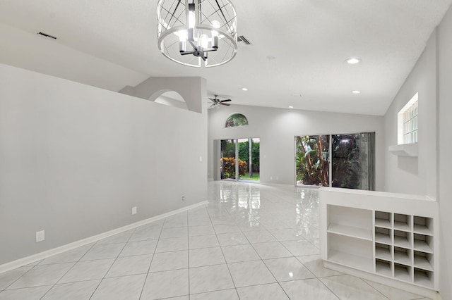 interior space featuring ceiling fan with notable chandelier, light tile patterned flooring, and lofted ceiling