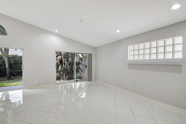 tiled empty room featuring a textured ceiling and lofted ceiling