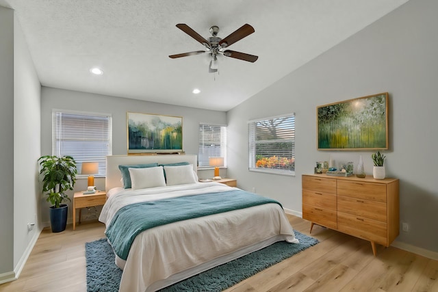 bedroom featuring ceiling fan, light wood-type flooring, a textured ceiling, and lofted ceiling