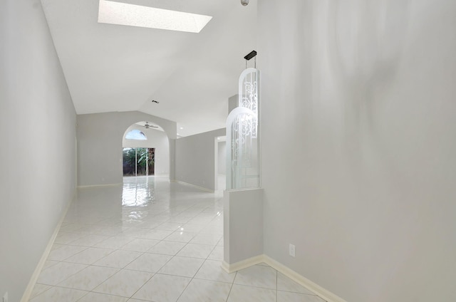 hallway with light tile patterned flooring and vaulted ceiling with skylight