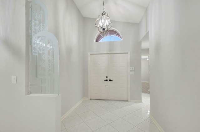 foyer entrance with light tile patterned floors, high vaulted ceiling, and an inviting chandelier