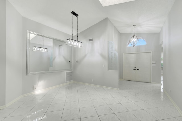 tiled entrance foyer with a chandelier and high vaulted ceiling