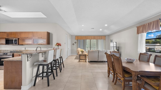 dining space with a textured ceiling, a skylight, light tile patterned floors, and plenty of natural light