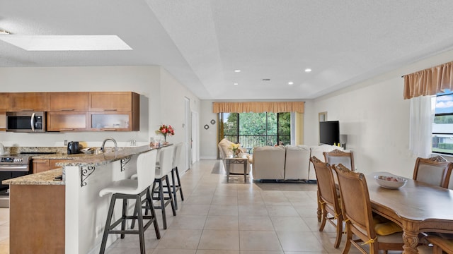 kitchen featuring a textured ceiling, light stone countertops, stainless steel appliances, and a wealth of natural light