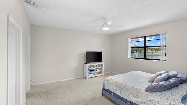 bedroom with ceiling fan, a textured ceiling, and carpet floors