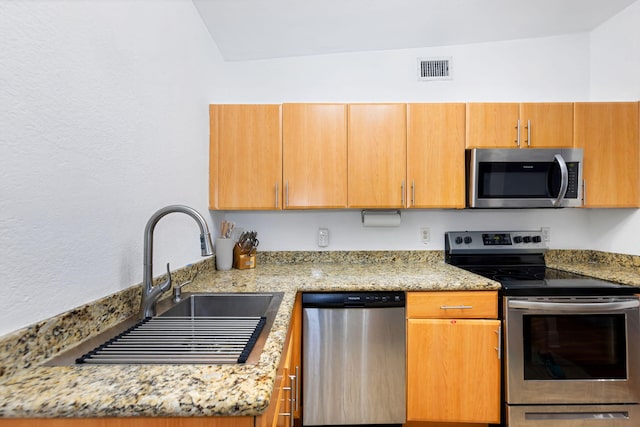 kitchen with light stone countertops, sink, and stainless steel appliances