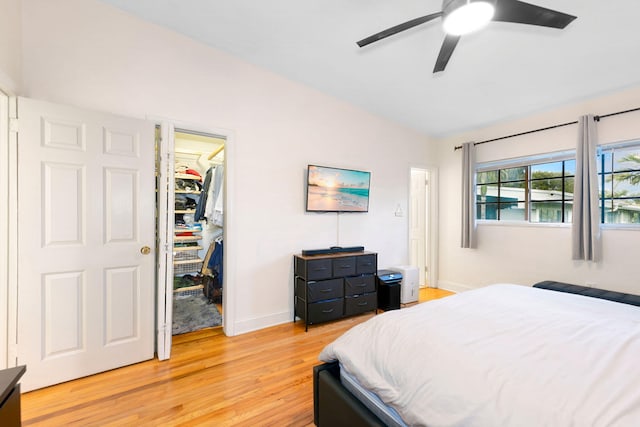 bedroom featuring ceiling fan, light wood-type flooring, a spacious closet, and a closet