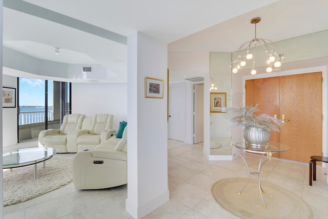 living room featuring a water view, light tile patterned floors, and a notable chandelier