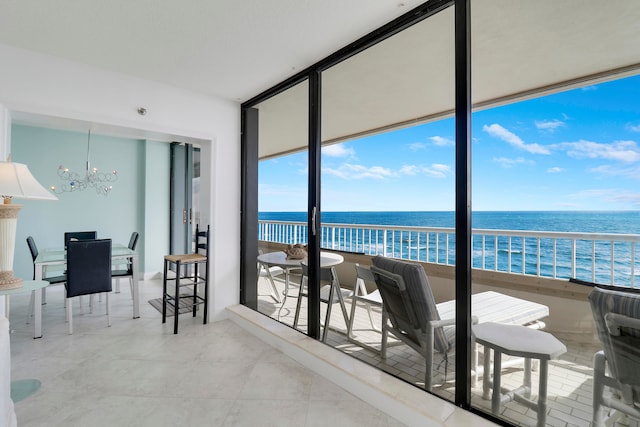 sunroom / solarium featuring a notable chandelier and a water view