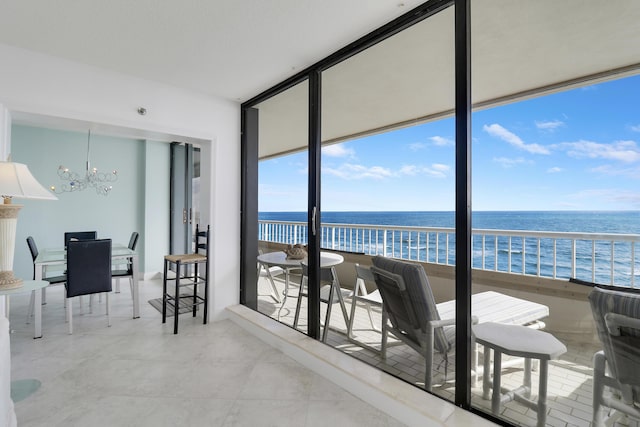 sunroom featuring a water view, plenty of natural light, and an inviting chandelier