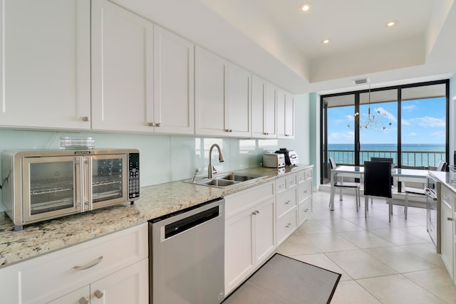 kitchen featuring light stone countertops, stainless steel dishwasher, sink, a water view, and white cabinets