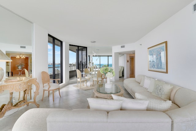 tiled living room with a chandelier, a water view, and a wall of windows