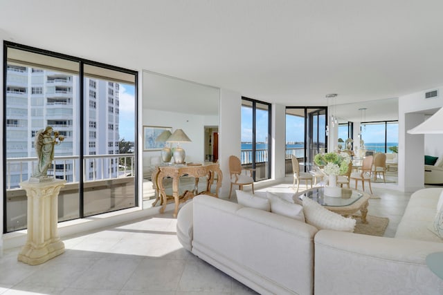 tiled living room featuring expansive windows, a healthy amount of sunlight, and a water view