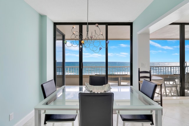 dining space featuring floor to ceiling windows, an inviting chandelier, a water view, tile patterned flooring, and a beach view