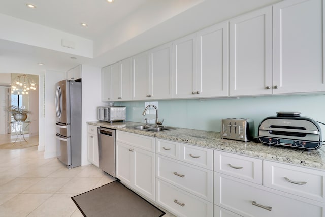 kitchen featuring appliances with stainless steel finishes, sink, light tile patterned floors, an inviting chandelier, and white cabinetry