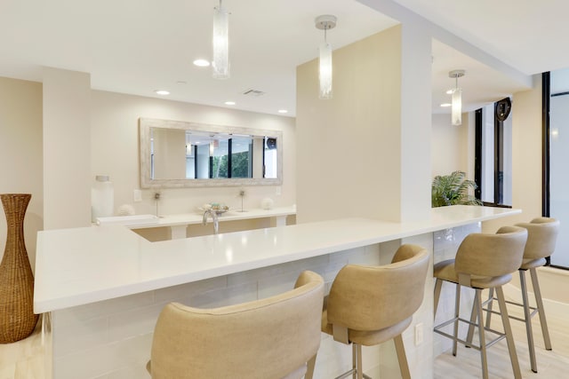 kitchen with kitchen peninsula, light tile patterned floors, decorative light fixtures, and a breakfast bar area