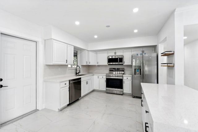 kitchen featuring white cabinetry, sink, stainless steel appliances, light stone counters, and backsplash