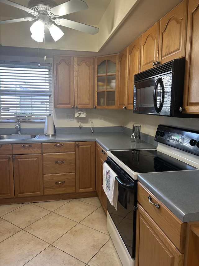 kitchen with light tile patterned floors, range with electric cooktop, brown cabinetry, black microwave, and a sink