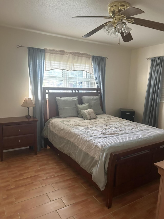 bedroom with a textured ceiling, wood finish floors, and a ceiling fan