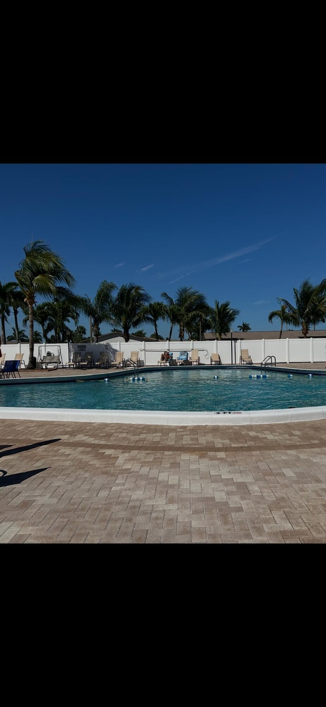 community pool with a patio area and fence