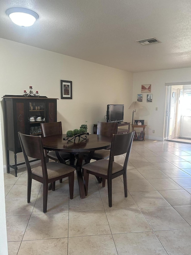 dining area featuring a textured ceiling, light tile patterned flooring, and visible vents