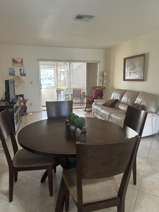 tiled dining space with a textured ceiling and ceiling fan