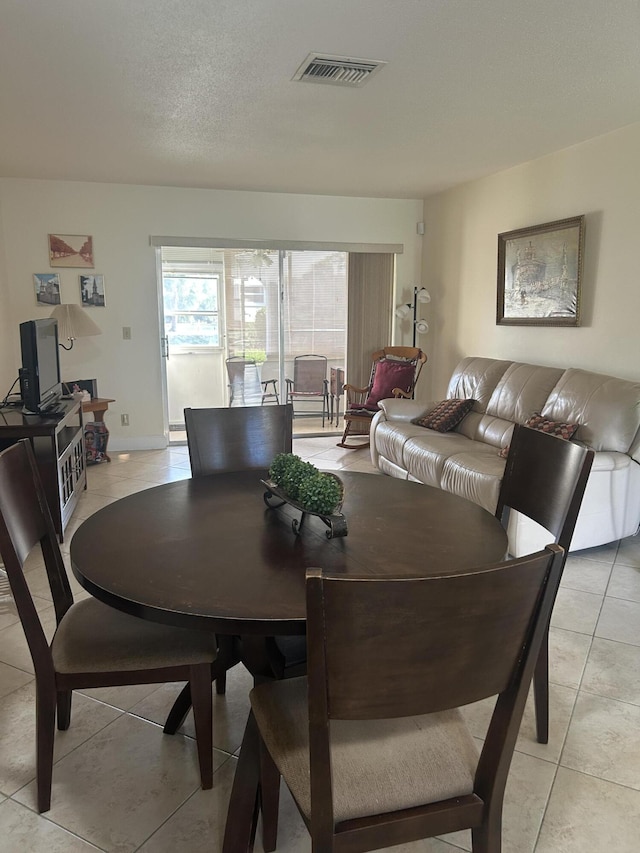 dining area with visible vents, a textured ceiling, and light tile patterned flooring