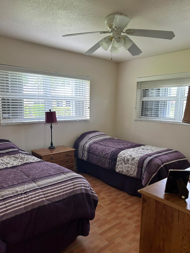 bedroom with ceiling fan, a textured ceiling, and light wood-type flooring