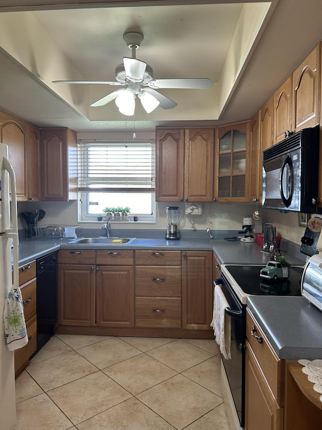 kitchen with light tile patterned floors, black appliances, brown cabinetry, and a sink