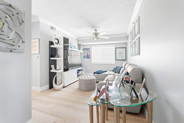 living room featuring a textured ceiling, ceiling fan, light wood-type flooring, and ornamental molding