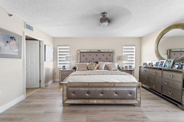 bedroom with ceiling fan, light hardwood / wood-style floors, and a textured ceiling