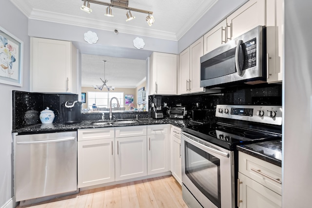 kitchen featuring tasteful backsplash, stainless steel appliances, sink, a notable chandelier, and white cabinets