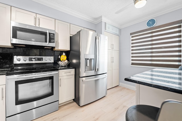 kitchen with backsplash, white cabinets, light wood-type flooring, ornamental molding, and appliances with stainless steel finishes