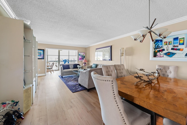 dining space with a chandelier, crown molding, light hardwood / wood-style floors, and a textured ceiling