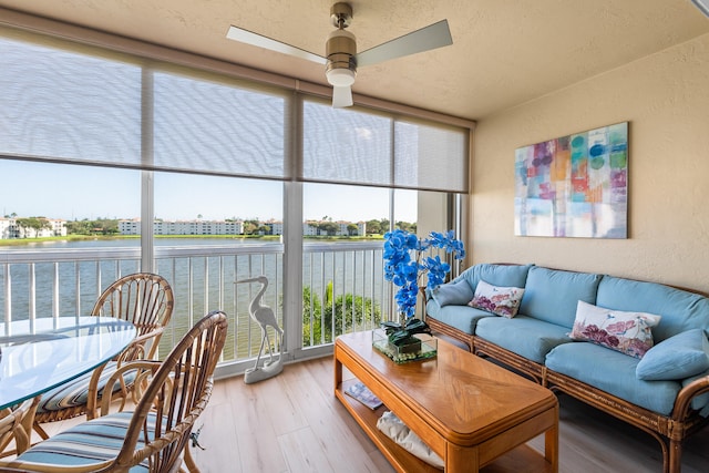 sunroom featuring ceiling fan and a water view