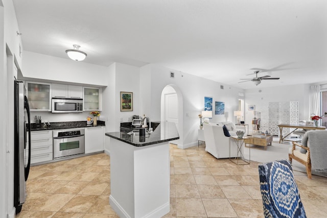 kitchen with stainless steel appliances, kitchen peninsula, ceiling fan, sink, and white cabinetry