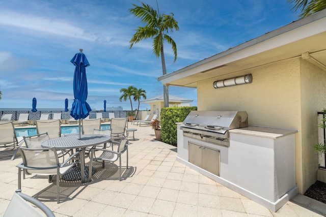 view of patio featuring a community pool, area for grilling, and exterior kitchen