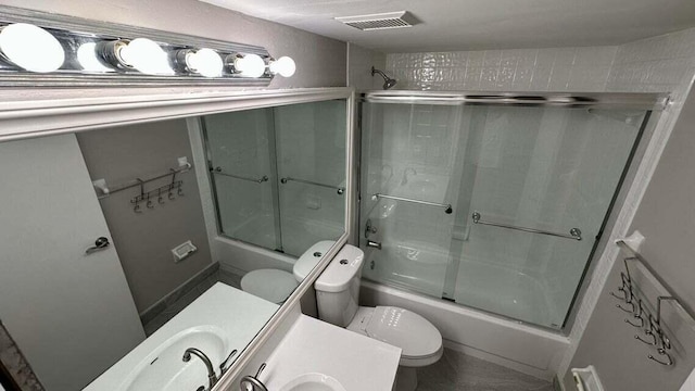 full bathroom featuring vanity, shower / bath combination with glass door, and toilet