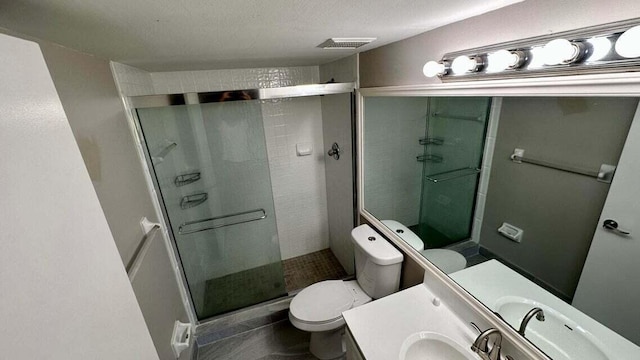 bathroom featuring vanity, toilet, a textured ceiling, and a shower with shower door