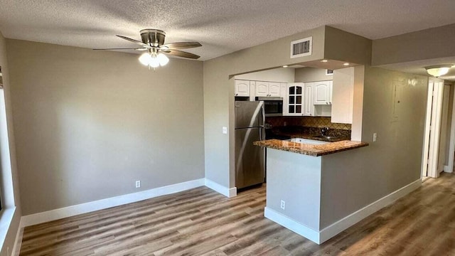 kitchen with kitchen peninsula, white cabinetry, hardwood / wood-style flooring, a textured ceiling, and stainless steel appliances