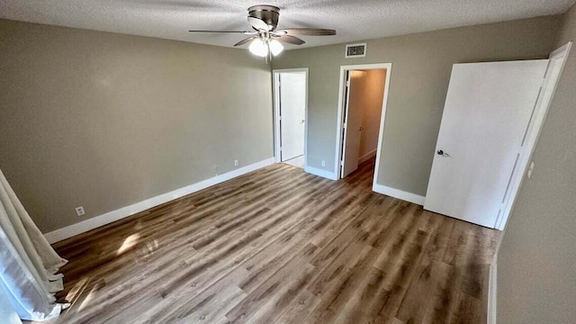 unfurnished bedroom with a textured ceiling, hardwood / wood-style flooring, and ceiling fan