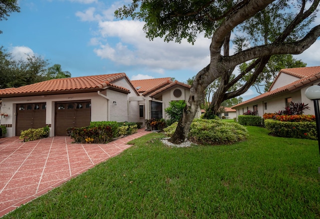 mediterranean / spanish home featuring a front yard and a garage