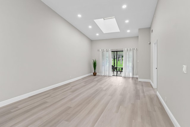 empty room with a skylight and light hardwood / wood-style floors