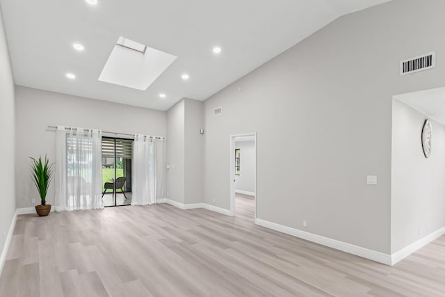 empty room with light hardwood / wood-style flooring, a skylight, and high vaulted ceiling